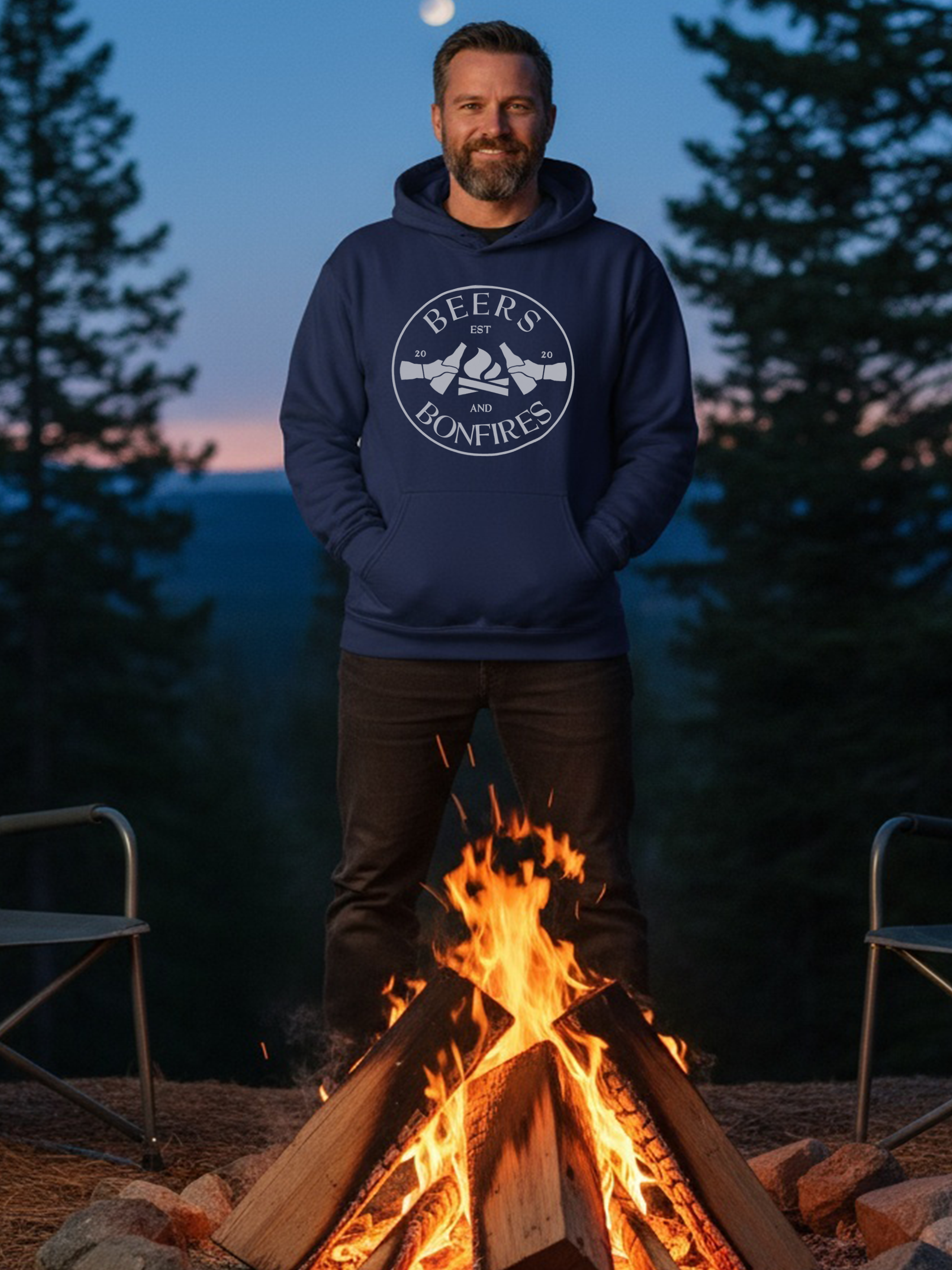 Man wearing a hoodie with a Beers and Bonfires design by a campfire at night.